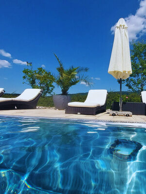 Außenpool mit Liegen und blauem Himmel im Wellnesshotel St. Gunther im Bayerischen Wald
