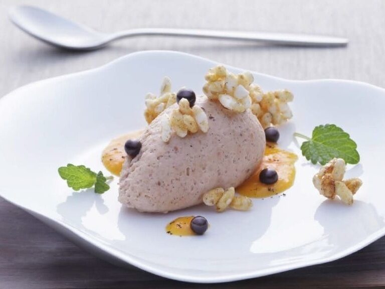 Ein kunstvolles Dessert auf stilvollem Geschirr angerichtet.